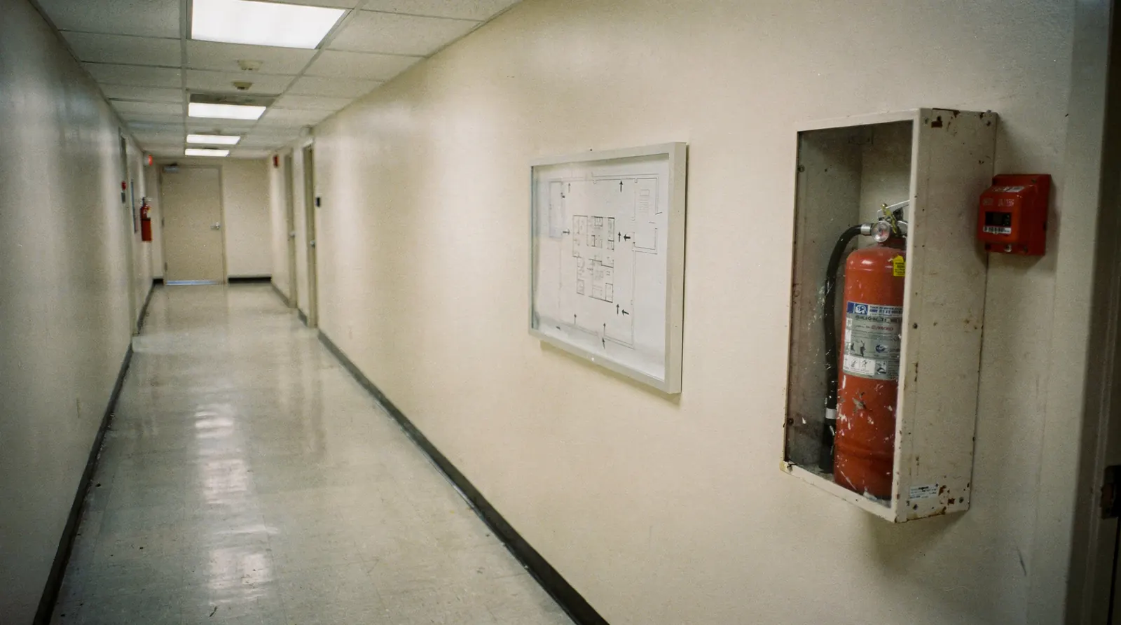 A laminated evacuation floor plan mounted beside a stairwell door in a commercial building, with an exit sign above it